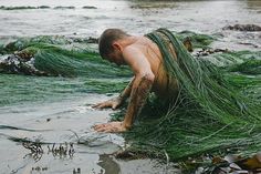 a man is covered in seaweed on the beach