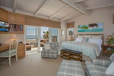 a bedroom with a bed, desk and chair in it next to a window overlooking the ocean