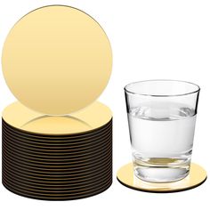 a stack of black and gold coasters with a glass of water next to it