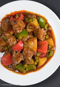 a white plate topped with meat and veggies covered in gravy on top of a table