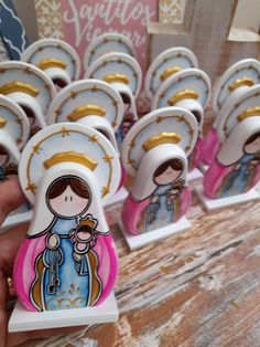 a hand is holding up small magnets with pictures of the virgin mary on them