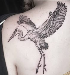 a woman's back with a bird tattoo on it