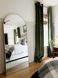 a bedroom with a large mirror on the wall and a bed in the room behind it