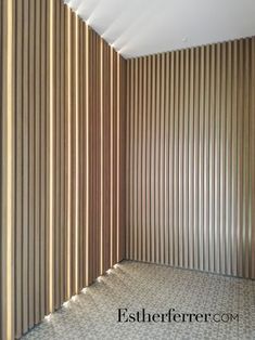 an empty room with wooden slats on the wall and tiled floor in front of it