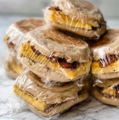 several sandwiches wrapped in plastic sitting on top of a marble countertop next to each other