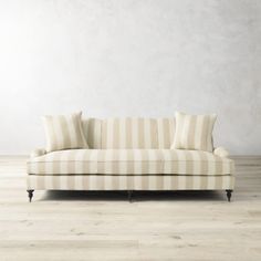 a striped couch sitting on top of a hard wood floor next to a white wall