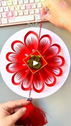 someone is making a paper flower decoration on the computer desk with their hand and mouse