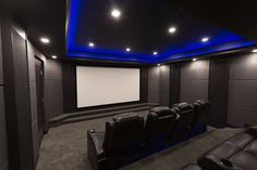 a home theater with black leather seats and blue lighting