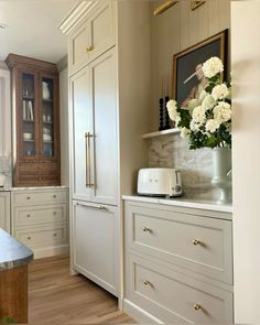 a kitchen with white cabinets and flowers in the vase on the counter top next to the oven