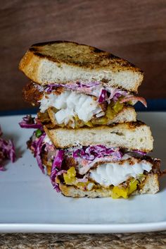 a sandwich cut in half on a plate with coleslaw and mayonnaise