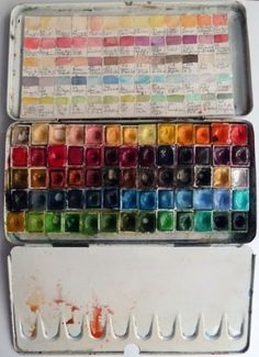 an old paint box filled with lots of different colored watercolors on it's side