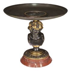 a bronze plate with a small statue on it's base and an oval tray