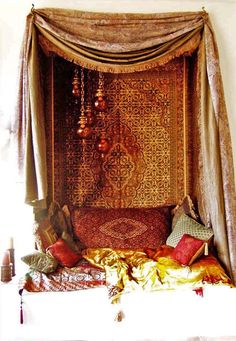 a canopy bed with many pillows on top of it and a chandelier hanging from the ceiling