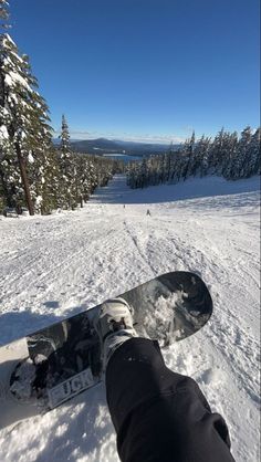 a person standing on top of a snow covered slope with their feet in the air