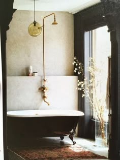 a bath tub sitting next to a window in a bathroom on top of a rug