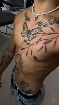 a man with tattoos on his chest standing in front of a table