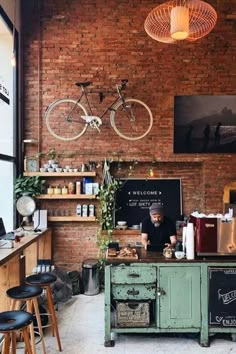 a man is behind the counter in a coffee shop with two bicycles hanging above it