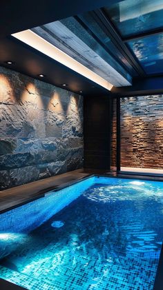 an indoor swimming pool with stone walls and blue water in the foreground, surrounded by dark wood flooring