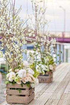 three wooden boxes filled with flowers on top of a table