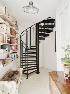 there is a spiral staircase in the living room with bookshelves on either side