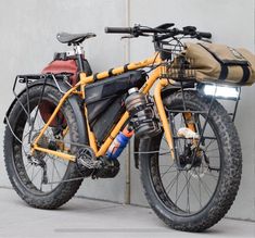 a yellow bicycle parked next to a wall with a bag on it's back