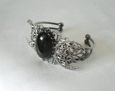 This beautiful silver plated cuff bracelet has a silver plated triple moon design and a large obsidian setting. Adjustable. Adjustable Mystical Silver Bracelet, Adjustable Silver Mystical Bracelet, Gothic Silver Bracelet, Silver Gothic Bangle, Handmade Silver Gothic Bracelet, Handmade Silver Gothic Bracelets, Handmade Gothic Silver Bracelets, Gothic Bangle Bracelet For Gift, Adjustable Gothic Crescent Jewelry