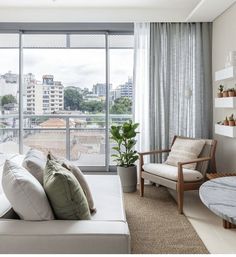 a living room filled with furniture and a large window overlooking a cityscape in the distance