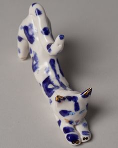 a ceramic cat figurine with blue spots on it's body and tail