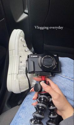 a person holding a camera in their hand while sitting on a car seat with the words vlogging every day