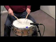 a man sitting on the floor with drums in front of him and holding two sticks