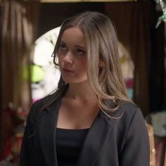 a woman standing in front of a mirror wearing a black top and blazer jacket