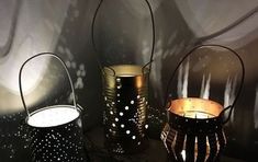 three metal lanterns sitting next to each other on a table