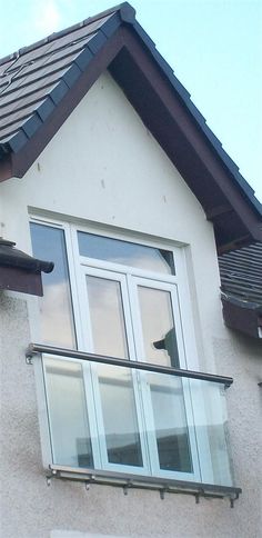 a cat sitting on top of a window sill in front of a white house