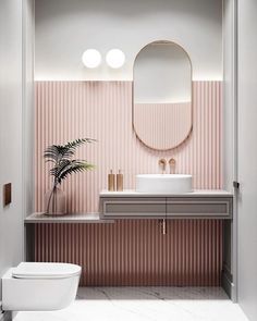 a bathroom with pink wallpaper and a round mirror above the sink, along with a potted plant