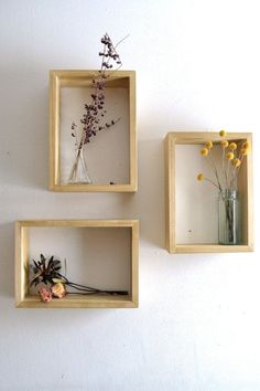 three square wooden shelves with vases and flowers in them hanging on the wall next to each other