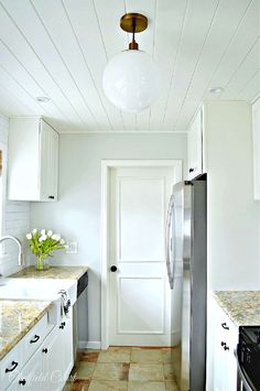 a kitchen with white cabinets and marble counter tops, along with a stainless steel refrigerator