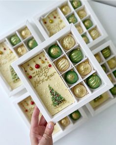 a hand holding a box filled with assorted decorated cookies and pastries in it