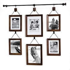 a group of pictures hanging on a wall next to a metal bar with some clothes pins