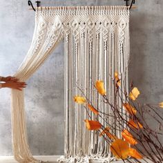 a white curtain hanging on the side of a wall next to a vase with flowers