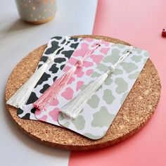 the cork coasters are decorated with tassels and pink, green, black and white designs