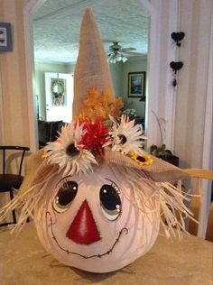 a decorated pumpkin with a scarecrow's hat on it sitting on top of a table