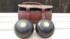 two black bowling balls sitting on top of a wooden table next to a brown bag