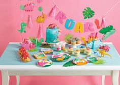 a birthday party with decorations and food on a table in front of a pink wall