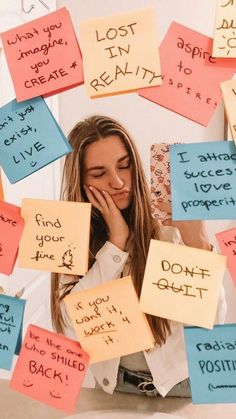 a woman sitting on the floor surrounded by post it notes that say lost, love, and positive