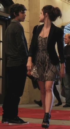 a man and woman are walking down the red carpet in front of an entrance to a building