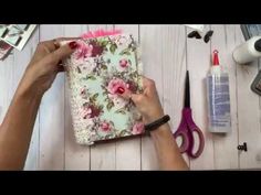 a woman is making a flowered notebook with scissors and other crafting supplies on the table