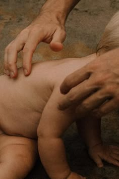 a baby is being held by someone's hand while another person holds it up