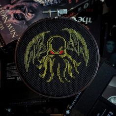 a cross stitch pattern with an octopus on it's face and some books in the background