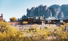 an old western town with mountains in the backgrouds and trees around it