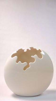 a white and brown vase sitting on top of a table